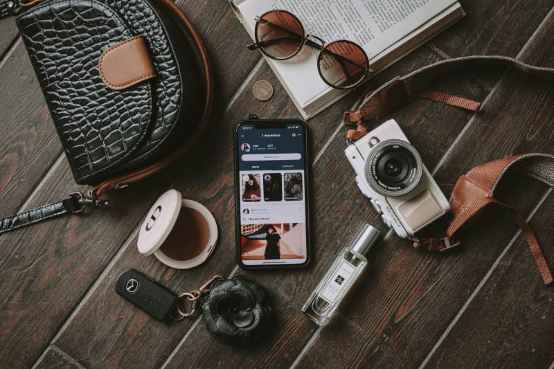  Reiseausrüstung mit Fotokamera, Mobilephone, Autoschlüssel und Buch. 